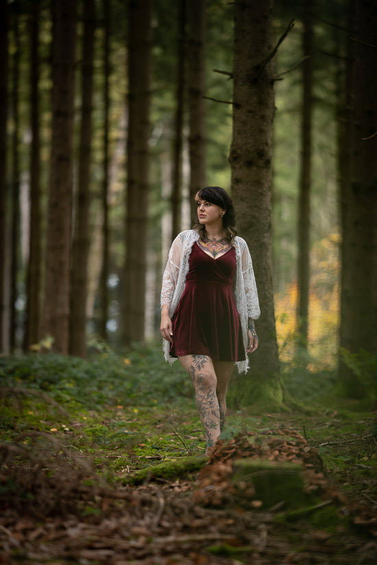 Frau läuft im Samtkleid im Wald
