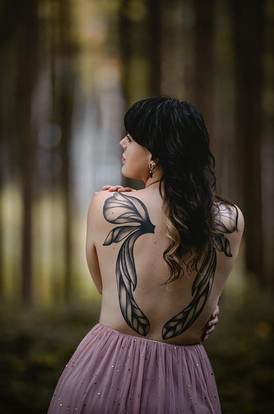 Rückenportrait einer Frau mit Tattoos